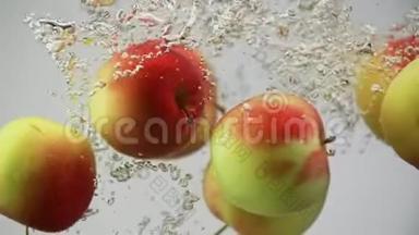 苹果红色和黄色在水中落下，随着气泡旋转，白色背景